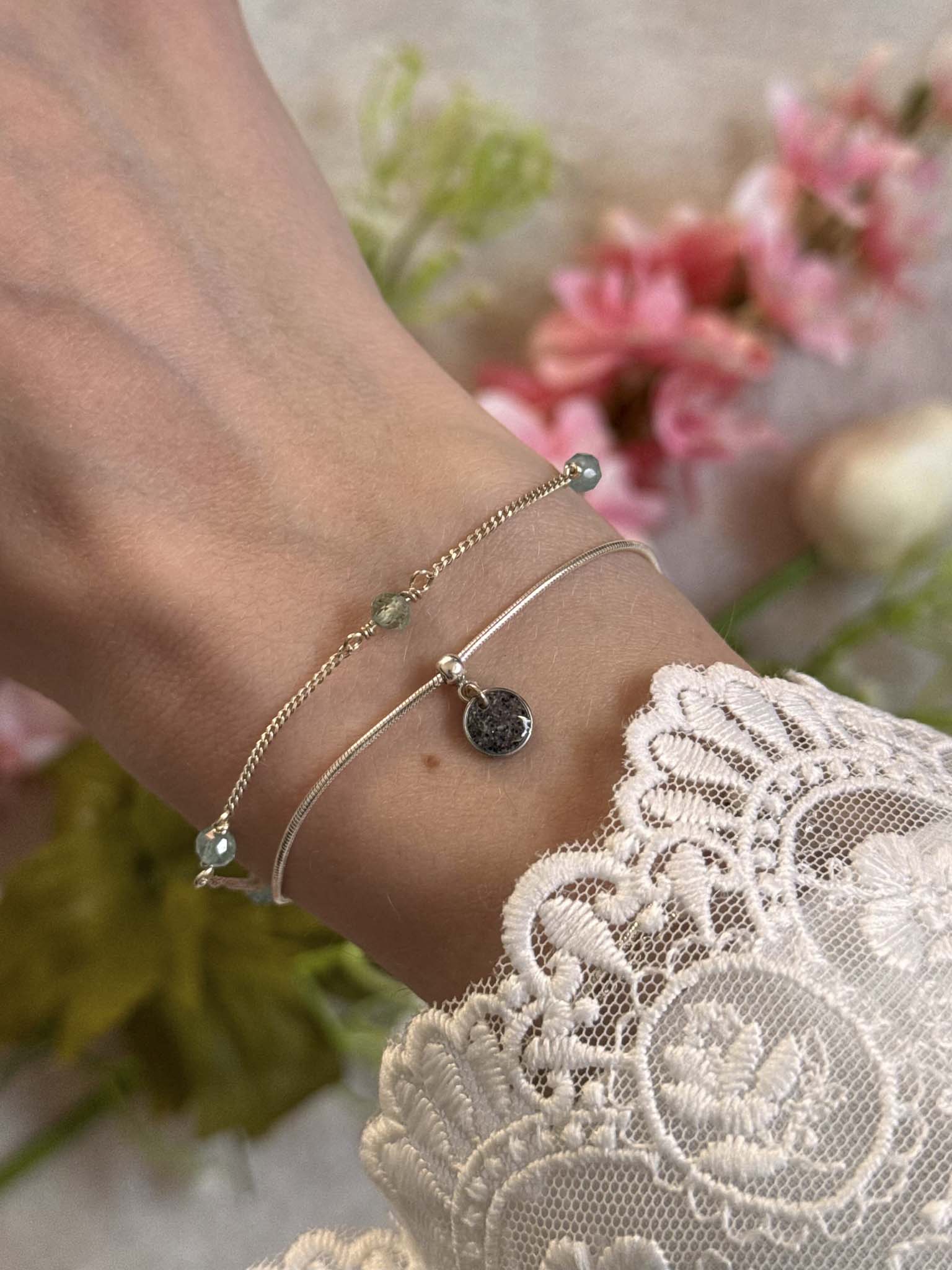 Bracelet lien fin à perles vertes et breloque ronde noire sur poignet