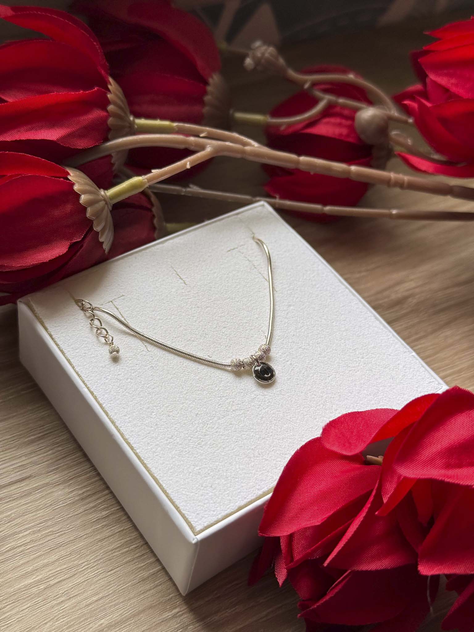 Collier fin doré avec pendentif rond noir sur chaîne, fermoir et anneau visibles