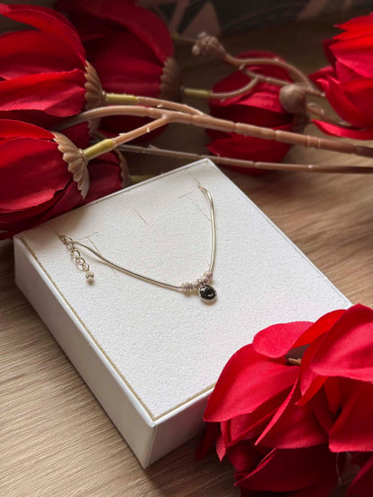 Collier fin doré avec pendentif rond noir sur chaîne, fermoir et anneau visibles