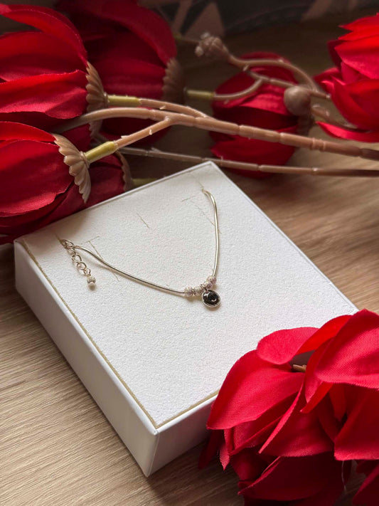 Collier fin doré avec pendentif rond noir sur chaîne, fermoir et anneau visibles