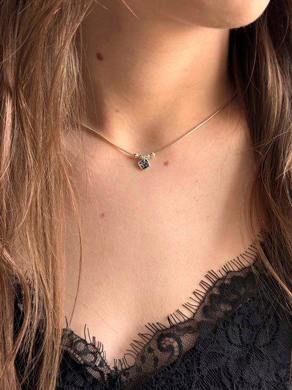 Collier Comète avec pendentif rond noir et maillons délicats, porté au cou