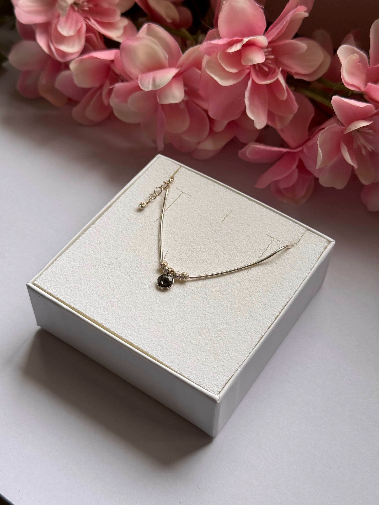Collier doré avec pendentif rond noir et chaînette, petites perles près du fermoir