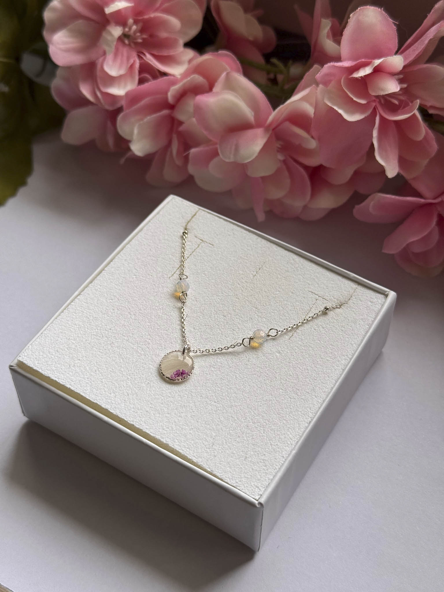 Collier Éclipse sur boîte : chaîne dorée et pendentif rond rose, petites perles